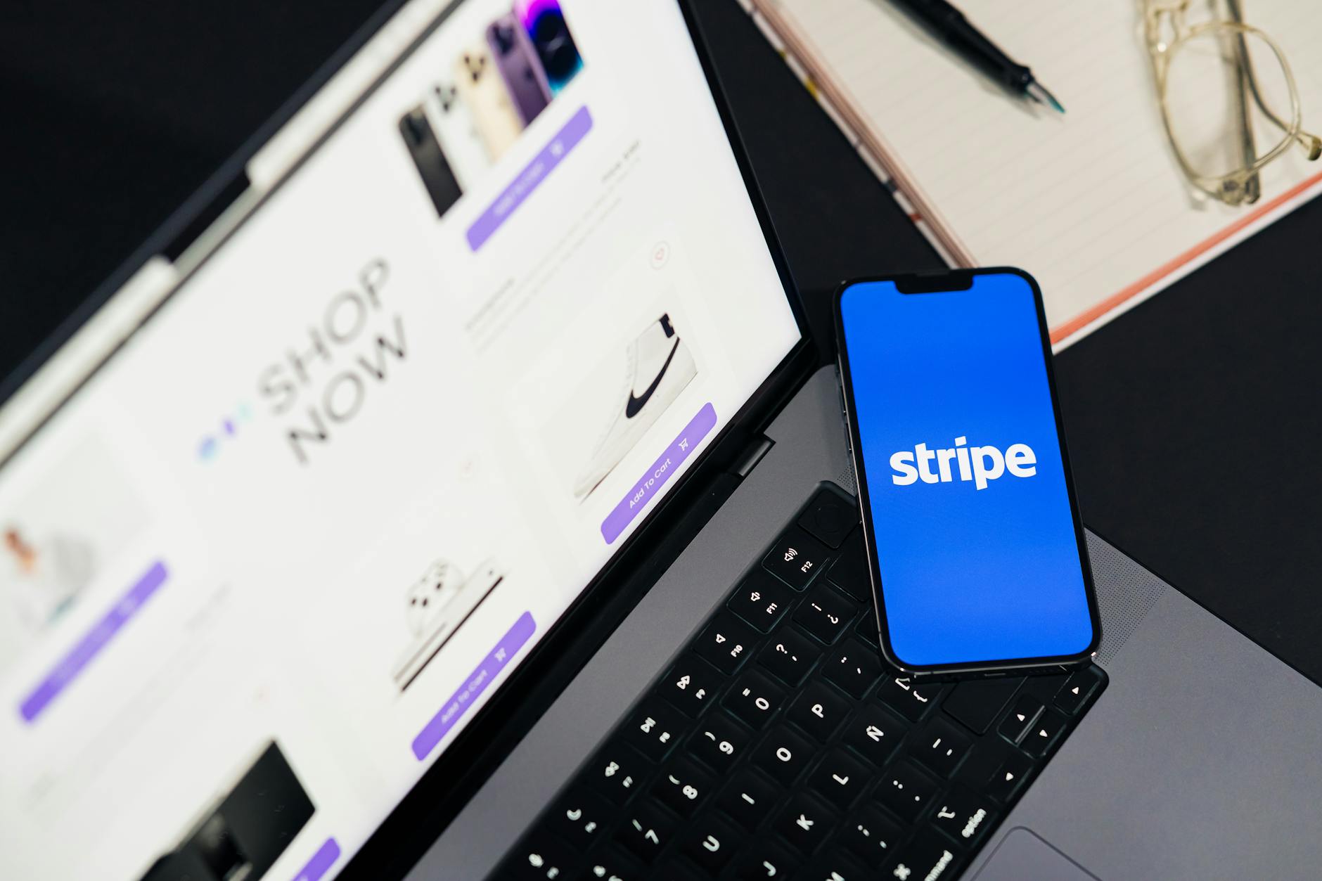 Smartfon z aplikacją płatniczą Stripe obok laptopa ze sklepem internetowym