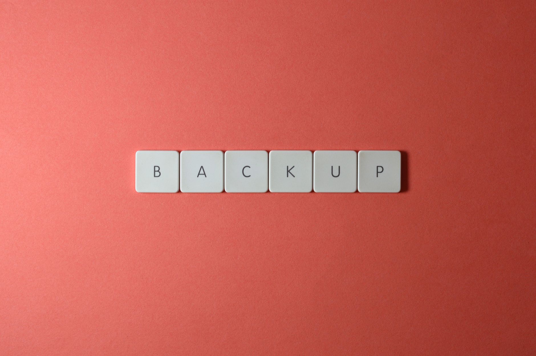 Klawisze klawiatury układające się w napis BACKUP na koralowym tle