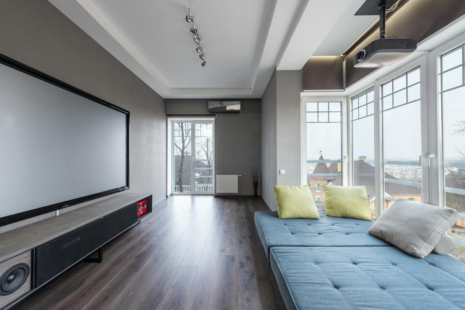 Nowoczesny salon z dużym telewizorem i sofą przy oknie