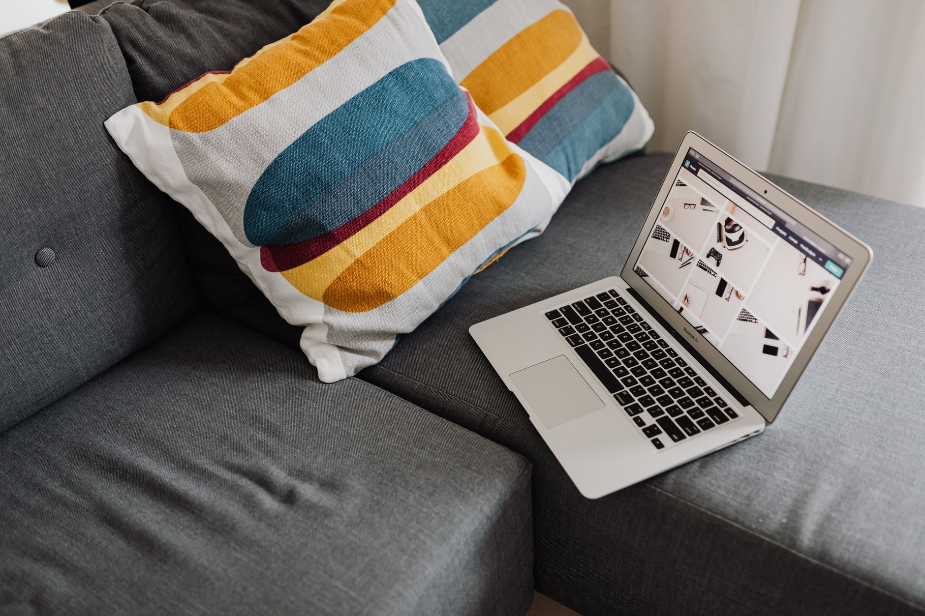 Inteligentne rekomendacje mebli: przyszłość personalizacji w e‑commerce Szara elegancka sofa z laptopem i kolorowymi poduszkami w domowym biurze