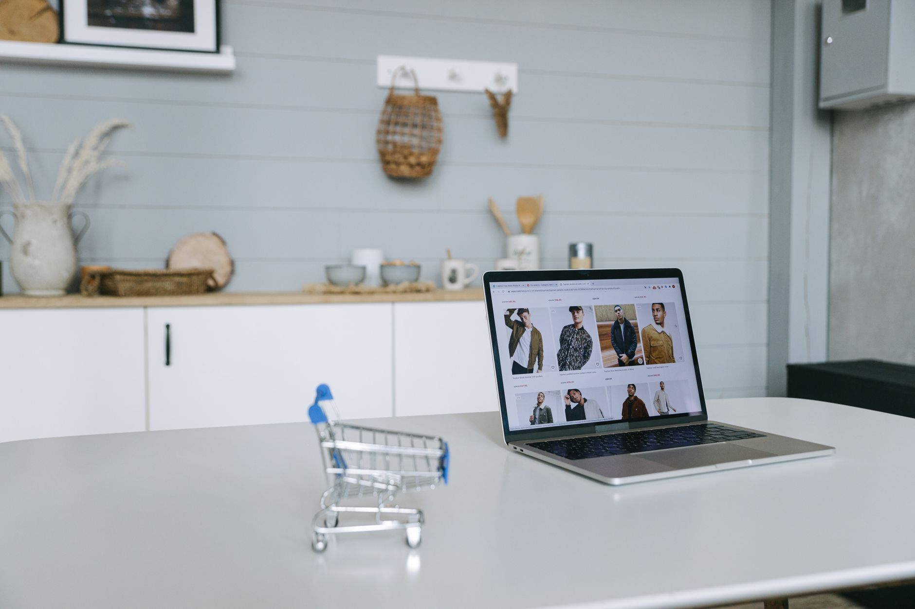 Laptop z portalem zakupowym i miniaturowym wózkiem na biurku